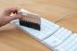 Preview: Eine Tastaturbürste mit dunklem Besatz entstaubt eine Tastatur.