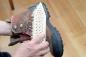 Preview: Eine Schuhschmutzbürste mit Fibre-Besatz wird zum Reinigen eines braunen Wanderschuhs verwendet. Dieser wird schräg gehalten.