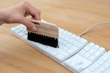 Preview: Eine Tastaturbürste mit schwarzem Besatz entstaubt eine Tastatur.