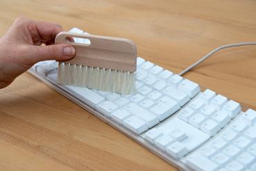 Preview: Eine Tastaturbürste mit hellem Besatz entstaubt eine Tastatur.