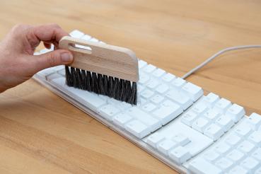 Preview: Eine Tastaturbürste mit dunklem Besatz entstaubt eine Tastatur.