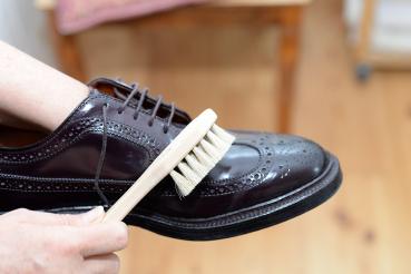 Schuhbürste mit hellem Besatz macht dunkle Schuhe sauber