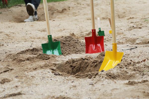 Kinderschaufeln in drei verschiedenen Farben sind in den Sand gesetzt