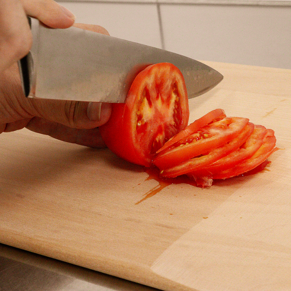 Das Pizzabrett aus Buchenholz auf dem Tomaten geschnitten werden